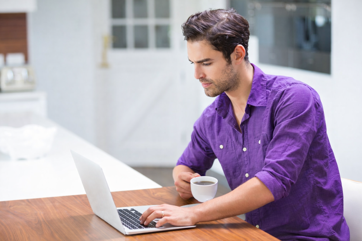Homem profissional trabalhando em um notebook sobre uma mesa com xícara de café ao lado em um ambiente de escritório representando: IVA dual: o guia completo da nova tributação de consumo.