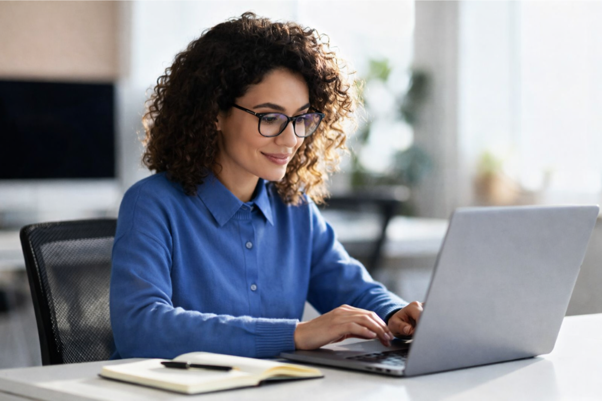Mulher profissional trabalhando em um notebook sobre uma mesa com agenda e caneta ao lado em um ambiente de escritório representando: Reforma Tributária: cronograma e entregáveis por ano: como preparar sua microempresa?