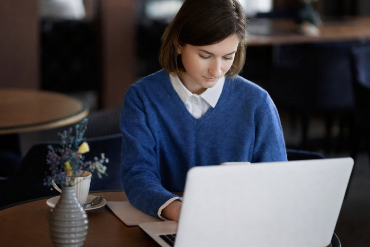 Mulher profissional trabalhando em um notebook sobre uma mesa em um ambiente de escritório representando: Qual o papel do contador na Reforma Tributária: como liderar a transição tecnológica da sua carteira?