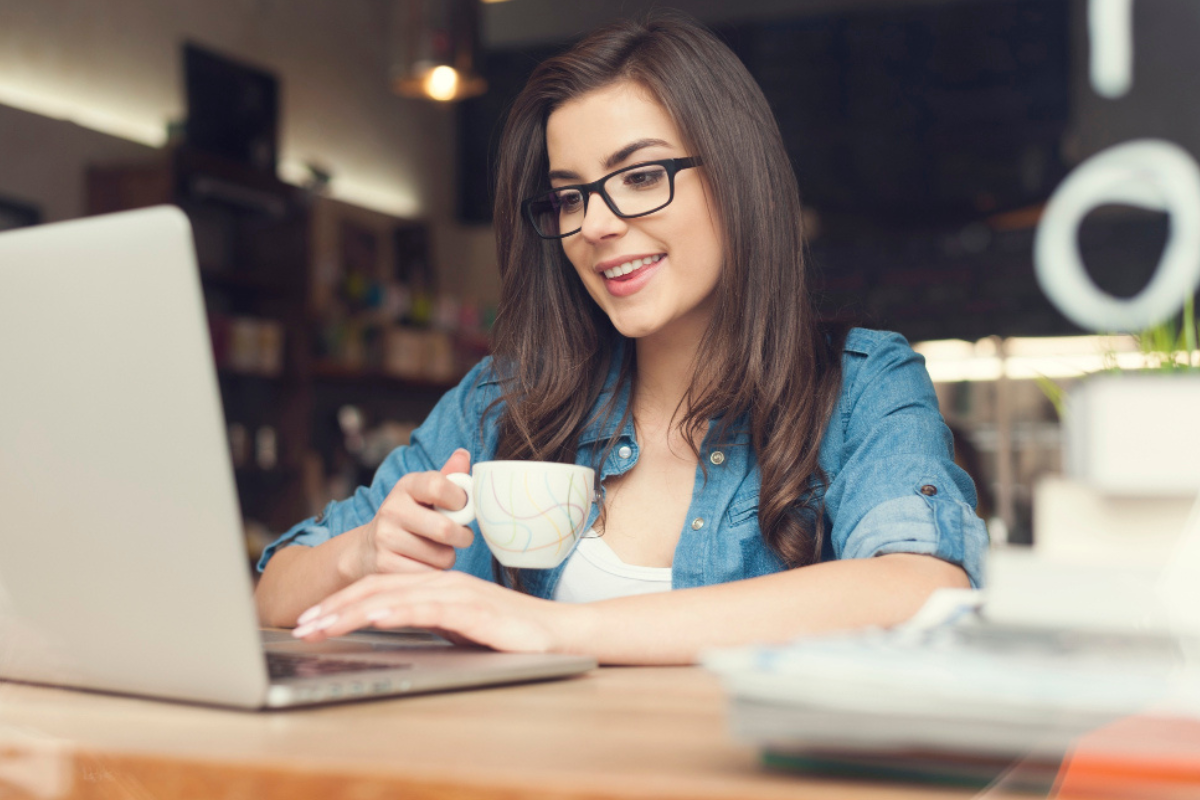 Mulher profissional trabalhando em um notebook sobre uma mesa em um ambiente de escritório representando: A não cumulatividade plena aumenta o crédito tributário das empresas?