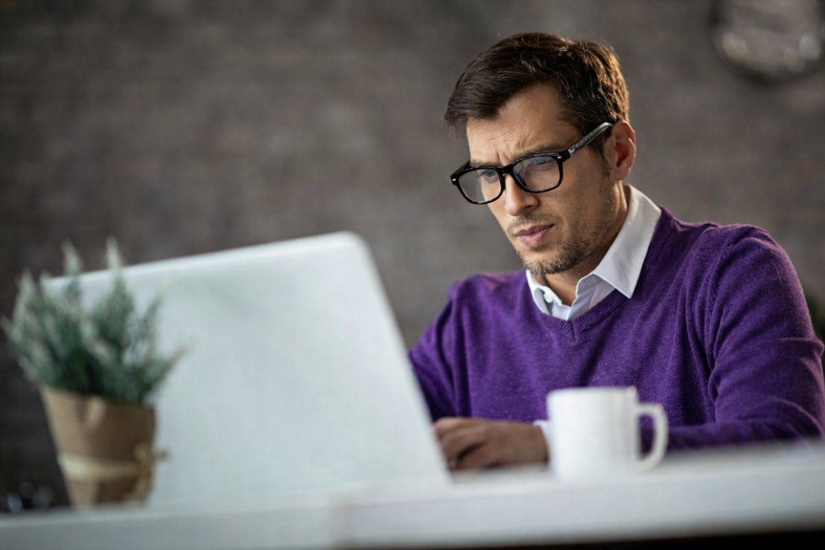 Homem profissional trabalhando em um notebook sobre uma mesa em um ambiente de escritório representando: Imposto seletivo: o que é e como funciona na reforma tributária?