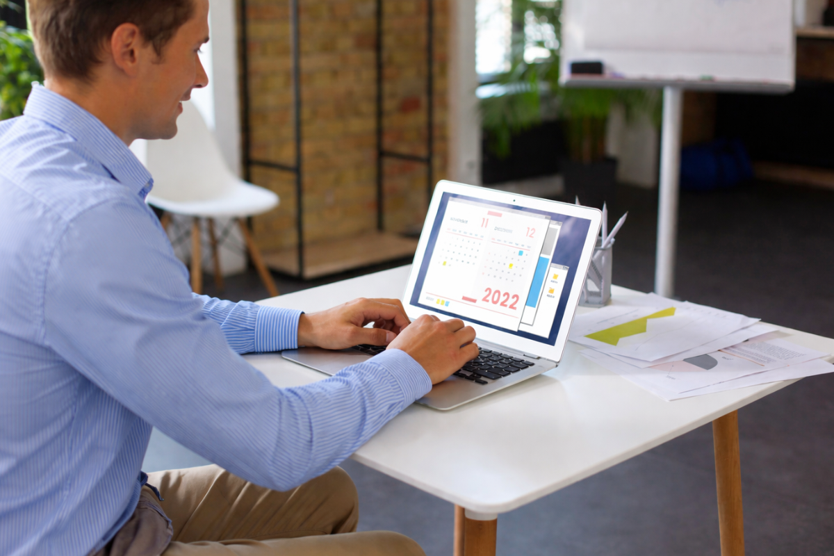 Homem profissional trabalhando em um notebook sobre uma mesa em um ambiente de escritório representando: Indicadores de desempenho que toda microempresa deveria acompanhar.