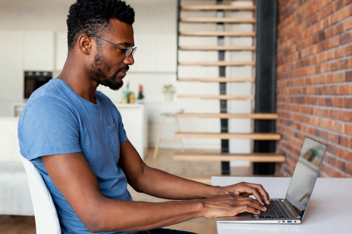 Homem profissional trabalhando em um notebook sobre uma mesa em um ambiente de escritório home office representando: Compliance tributário para micro e pequenas empresas.