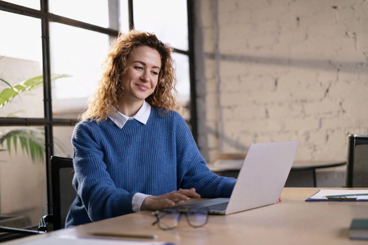 Mulher profissional trabalhando em um notebook sobre uma mesa em ambiente de escritório representando: Como integrar fiscal, financeiro e estoque na prática.