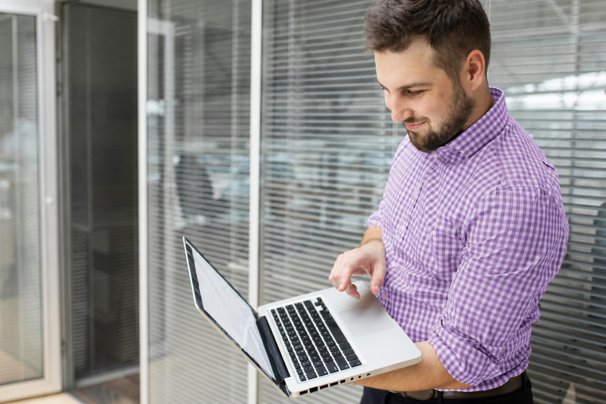 Homem andando usando um notebook em ambiente de escritório representando: Gestão baseada em dados: como aplicar em microempresas.