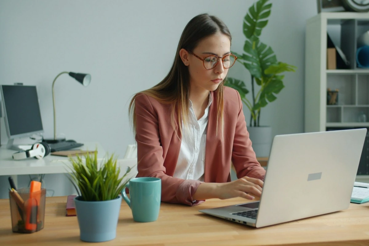 Empreendedora trabalhando em seu escritório em um notebook sobre Fluxo de caixa vs. regime de competência: qual o impacto na gestão de uma microempresa?