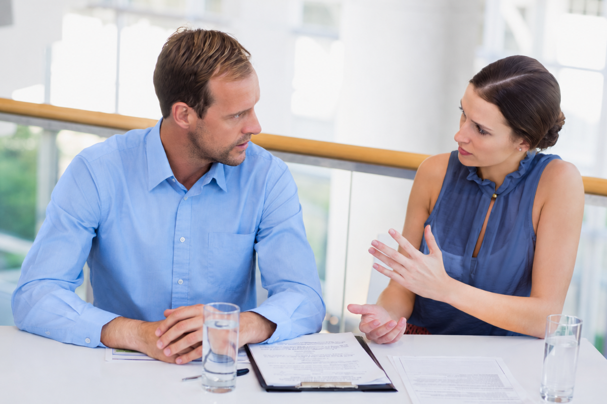 Homem e mulher sentados em uma mesa em uma reunião de negocios, representando: Direitos do consumidor na venda de ERP: o que o revendedor precisa saber para evitar processos